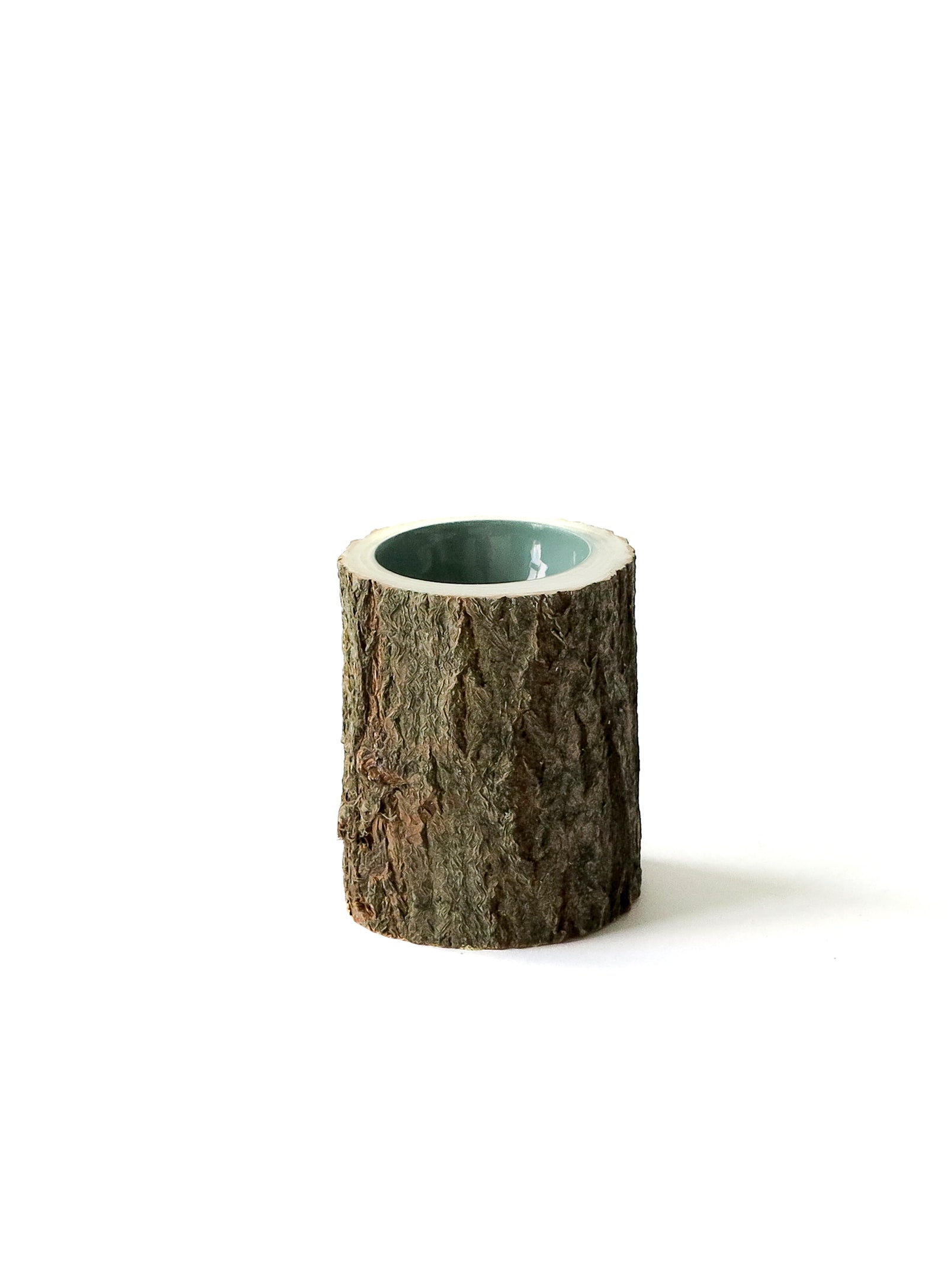 Small wooden bowl with bark exterior and a sage coloured interior.